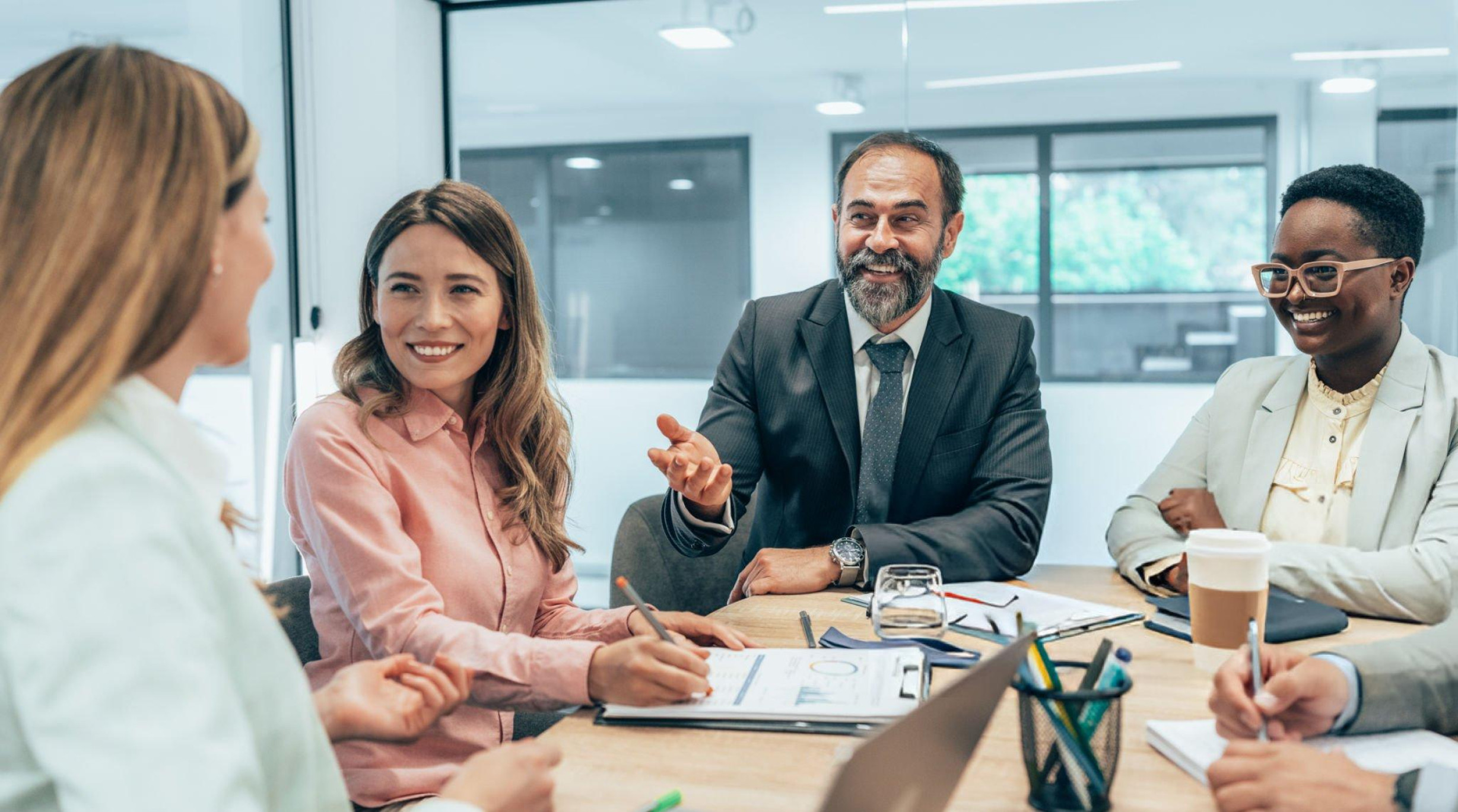 Diverse group of professionals smiling and discussing documents during a business meeting.