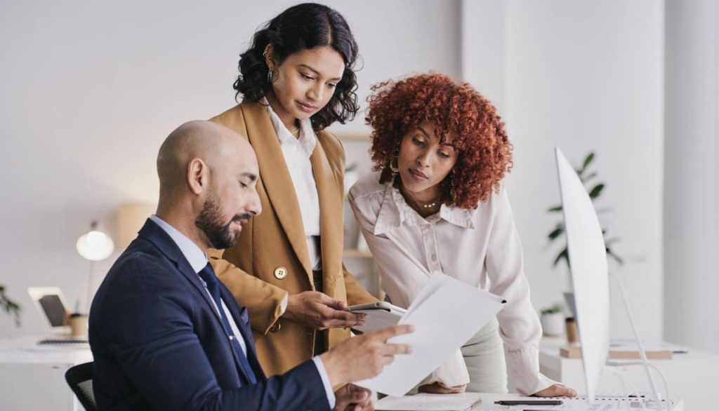 A diverse team of professionals collaborating in a modern office, reviewing documents together.